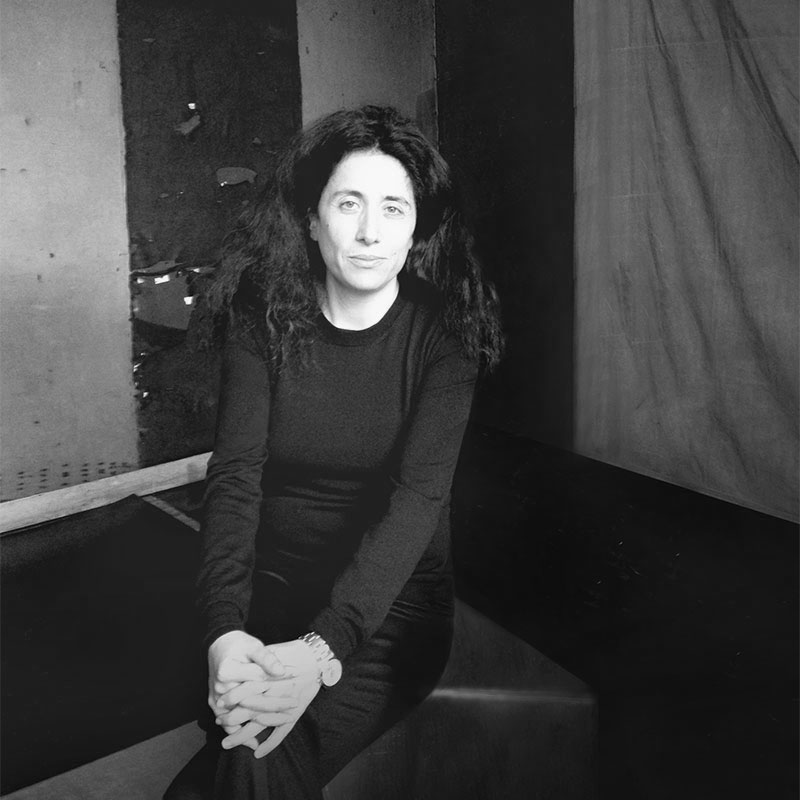 a black and white photo of a woman sitting on a bench