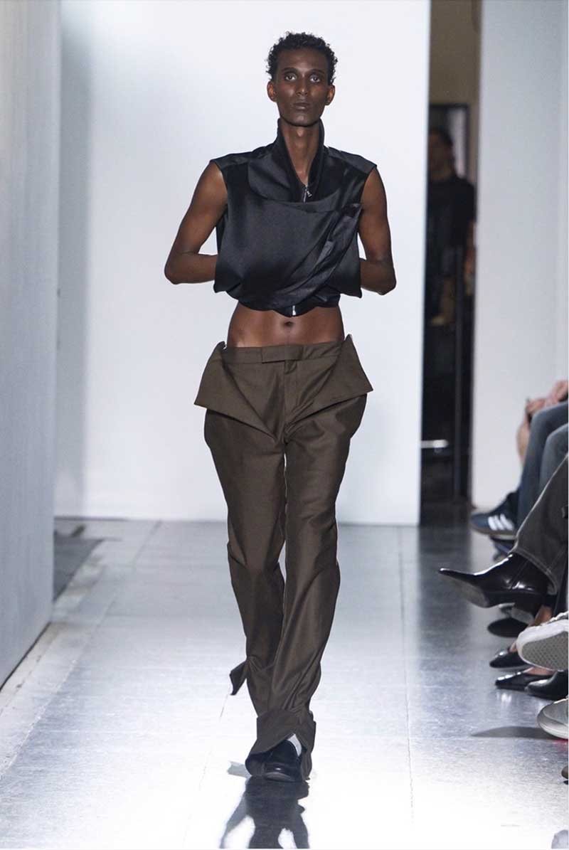 a woman walking down a runway in a black top