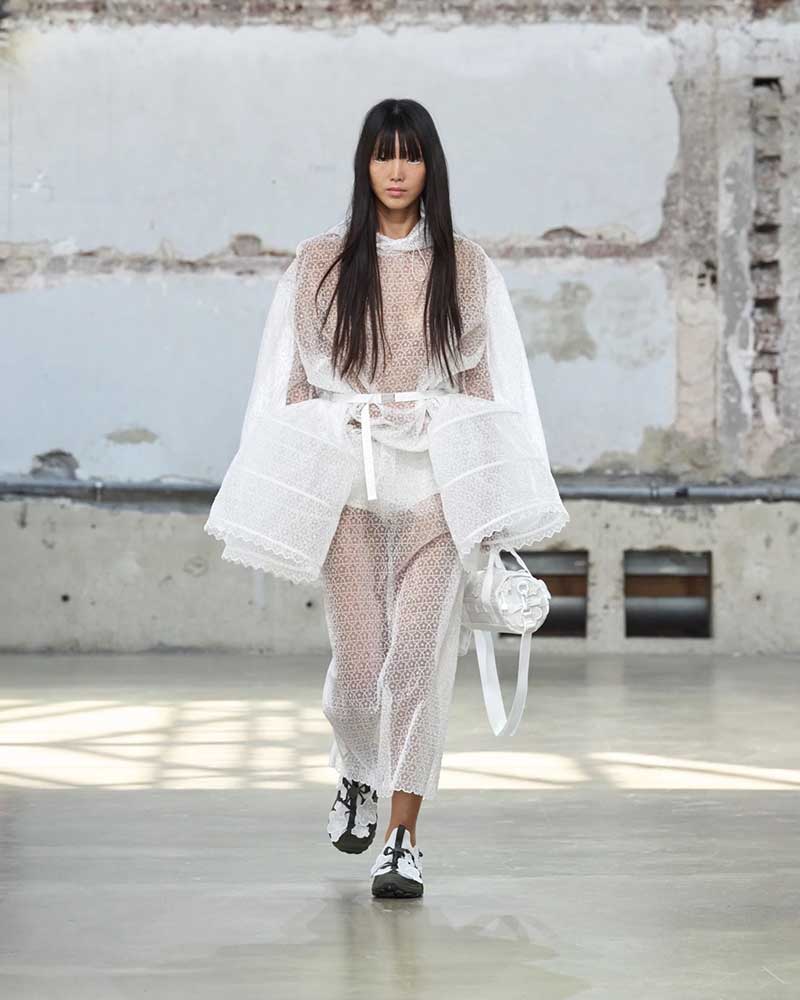 a woman walking down a runway wearing a white outfit
