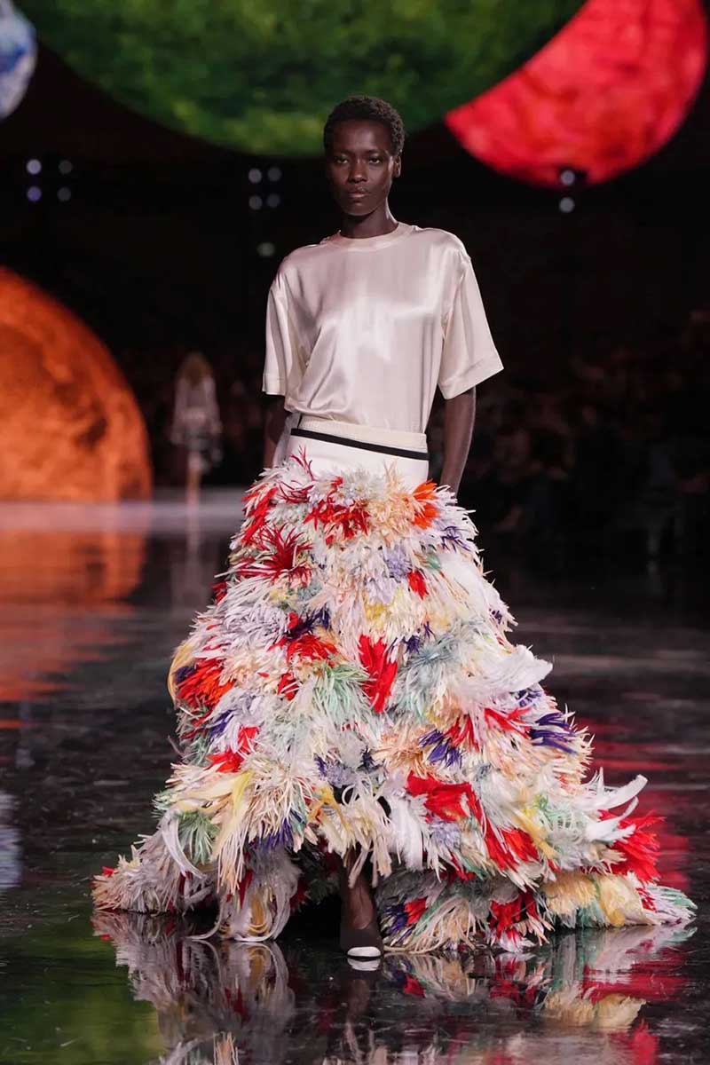 a model walks down the runway in a multicolored dress