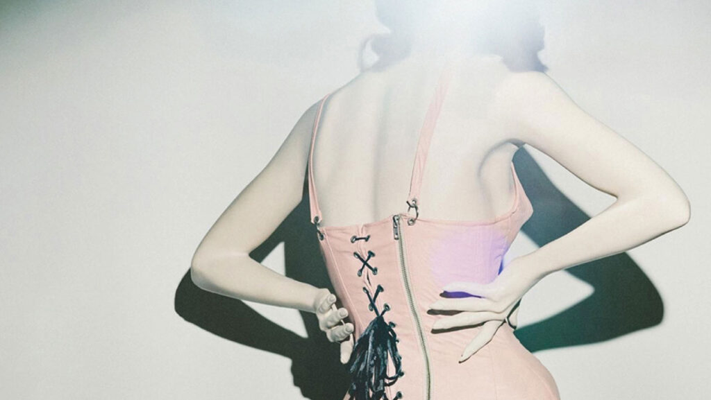 a woman in a pink corset with her hands on her hips