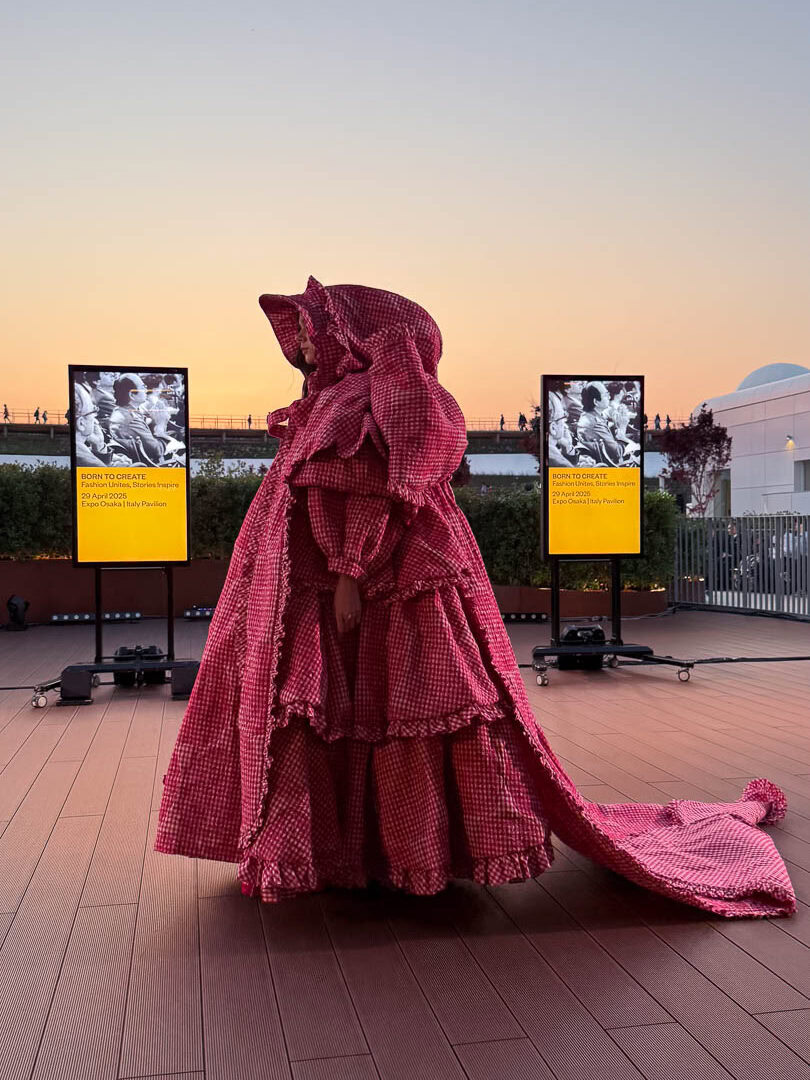 a woman in a pink dress standing in front of three televisions