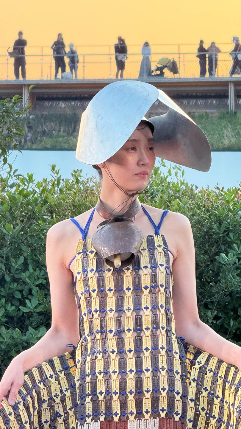 a woman in a dress and hat sitting on a bench