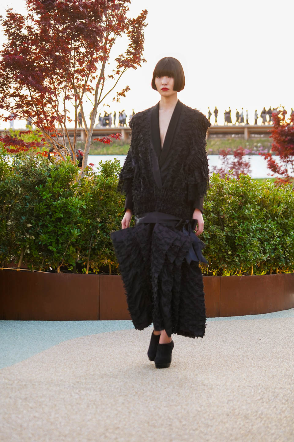 a woman in a black dress walking down a sidewalk
