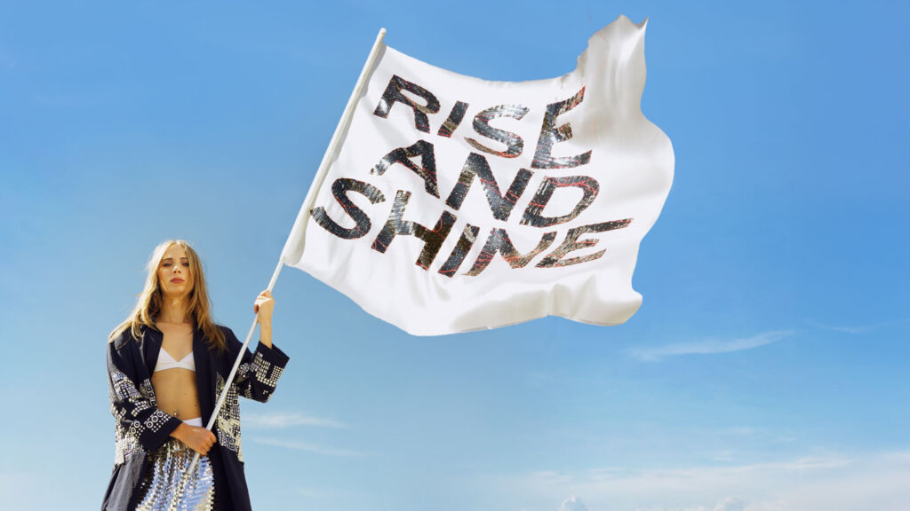 a woman holding a flag that says rise and shine