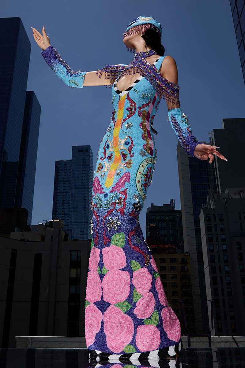 a woman in a colorful dress standing in front of tall buildings