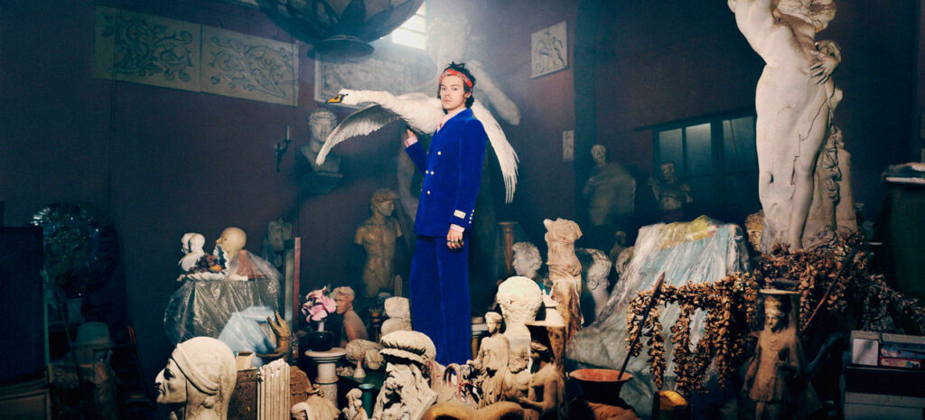 a woman in a blue dress standing in a room full of statues