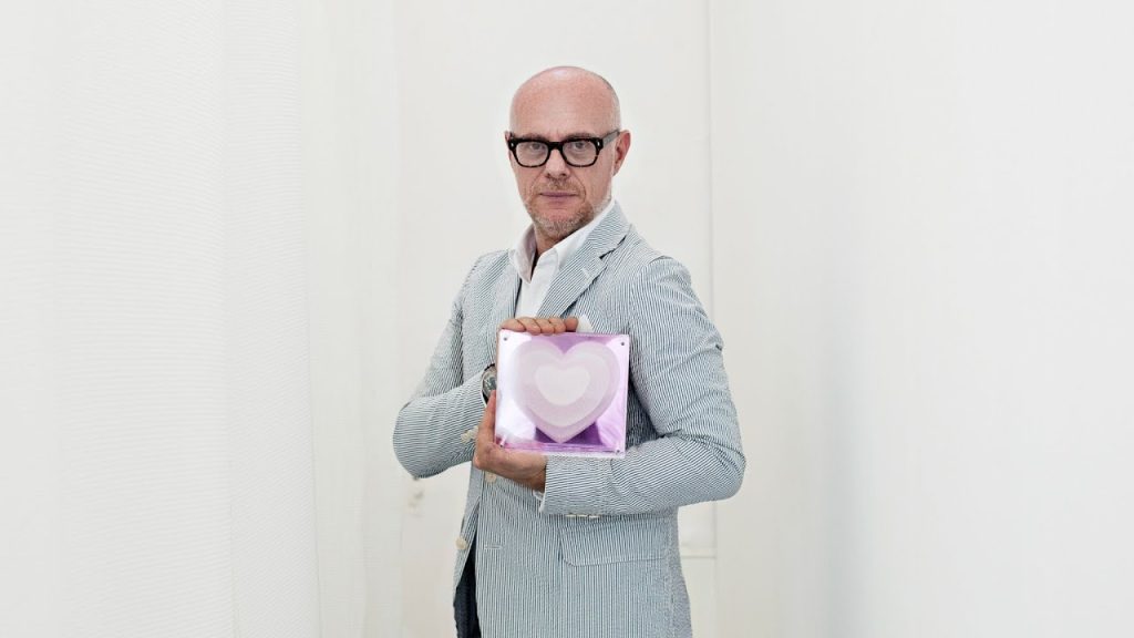 a man in a suit holding a box with a heart on it