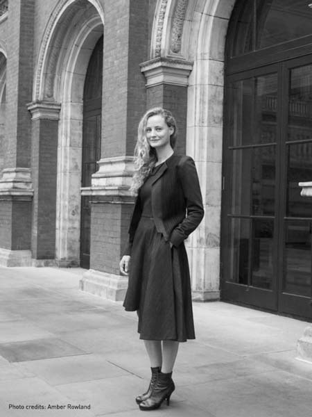 a woman standing on a sidewalk in front of a building