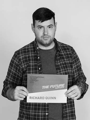 a man holding a sign that reads the future richard quinn