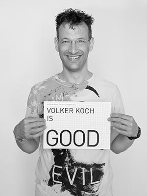 a man holding a sign that says, volker koch is good evil