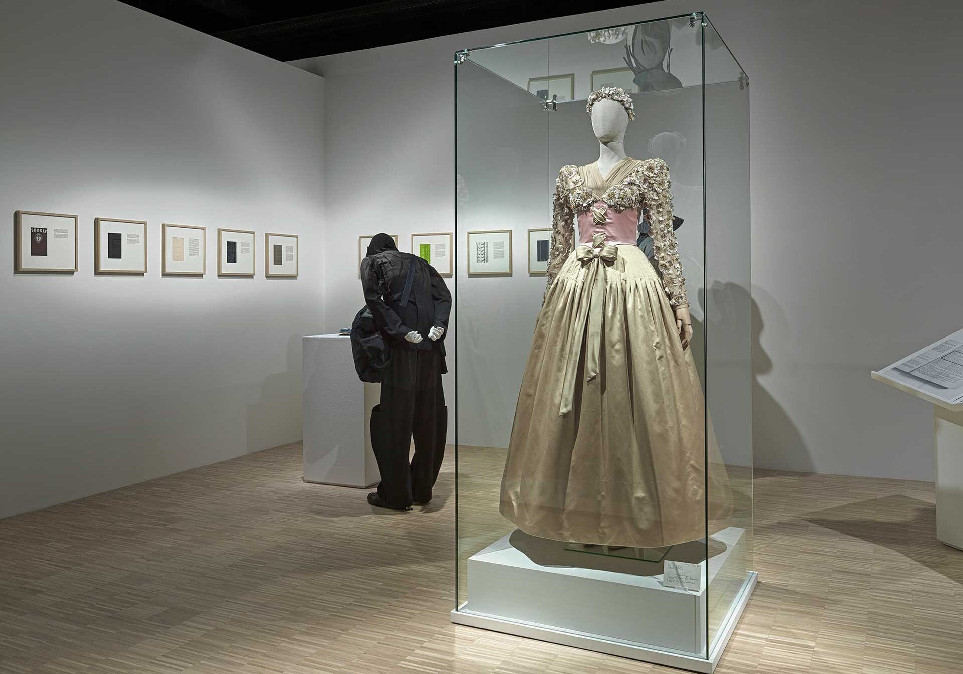 a person looking at a dress in a glass case