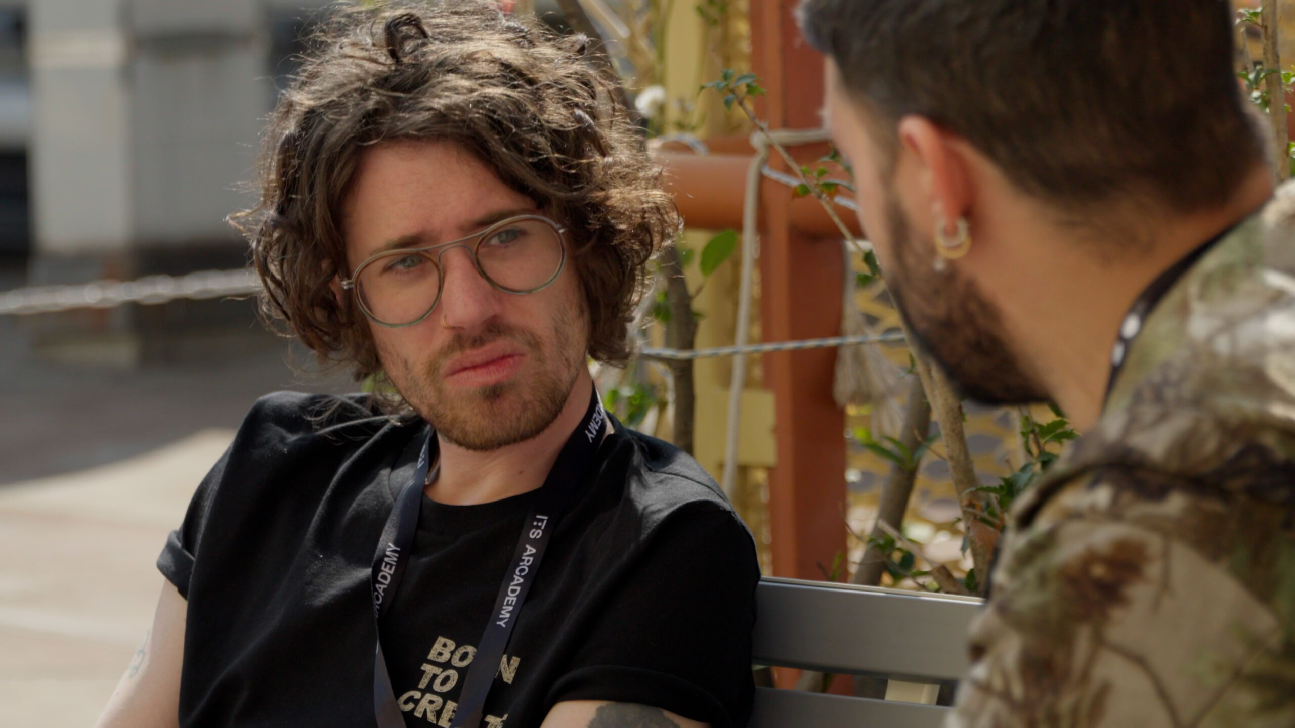 a man sitting on a bench talking to another man