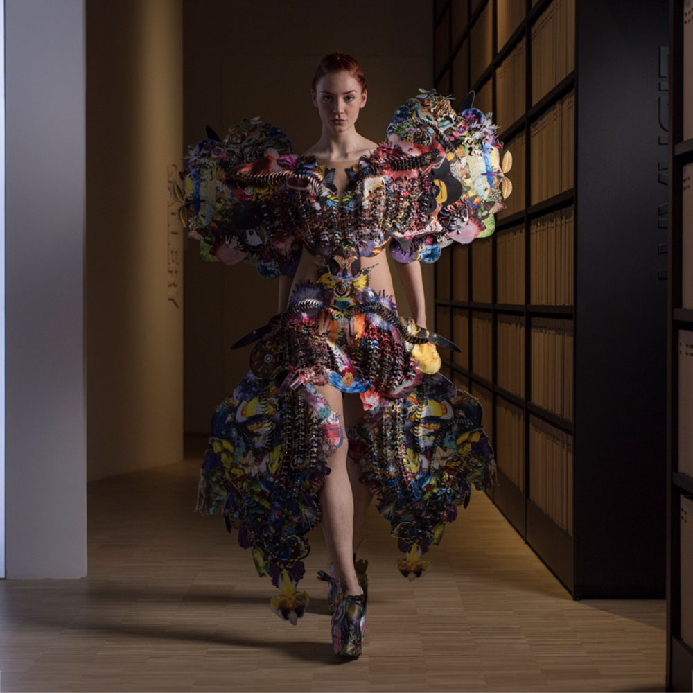 a woman walking down a runway in a colorful dress